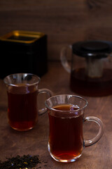 Turkish tea in traditional glass on the wooden table close-up. two glass cups of black tea with teapot on the dark brown background with copy space. vertical