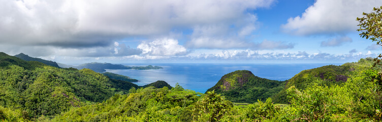 Fototapeta na wymiar Mahe Island coast panorama seen from Venn's Town - Mission Lodge wooden viewing platform, lush tropical forest with crystal blue Indian Ocean.