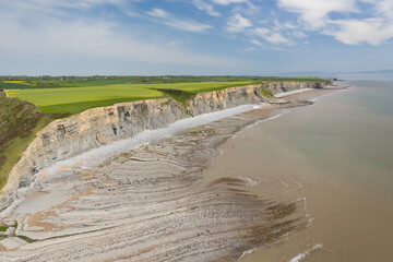 Aerial view of sea cliffs, rock formations and a sandy beach (Southerndown, Wales, UK)