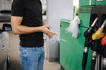 Close-up of man put on protective gloves on petrol station for refueling at gas station. Petrol...