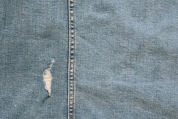 worn denim with one torn hole and vertical seam for background or wallpaper - 449696131