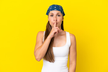 Young English woman isolated on yellow background showing a sign of silence gesture putting finger in mouth