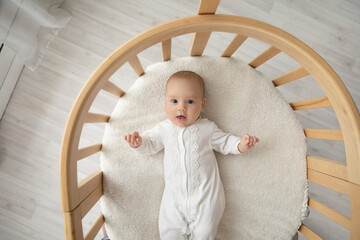 Top view portrait of cute little Caucasian baby infant kid child lying in children bassinet at...