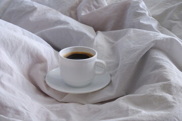 A cup of black coffee in bed. Interior. Cosiness.
