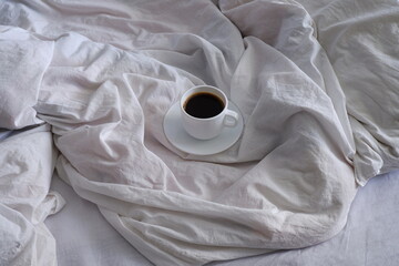 A cup of black coffee in bed. Interior. Cosiness.