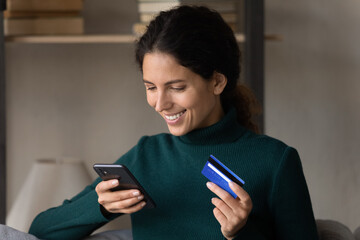 Close up happy woman using smartphone, paying online by credit card in internet store, smiling satisfied young customer holding smartphone, making secure internet payment, browsing banking service