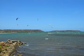 Poster Group of kiteboarders surfing across the water at Sint Joris Baai on the island of Curacao © skyf
