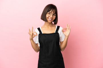 Restaurant waiter over isolated pink background showing ok sign with two hands