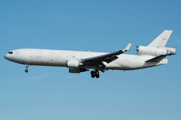 White cargo plane during a approach isolated on a blue sky background