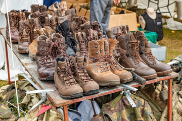 A selection of part worn and used army boots on a table display for sale at an army surplus stall