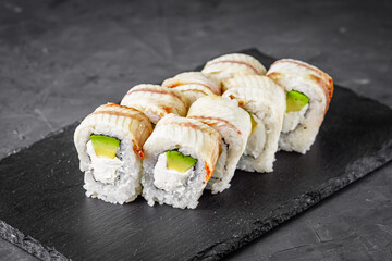 appetizing Philadelphia sushi roll with eel and avocado on a black stone plate