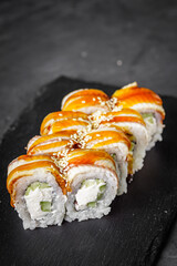 appetizing Philadelphia sushi roll with eel and cucumber on a black stone plate