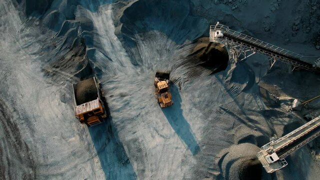 Large quarry dump truck. Loading rock in dumper. Loading coal into truck. Mining car machinery to transport coal. Open pit mine quarrying extractive industry stripping work. Big Yellow Mining Trucks