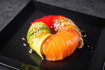 appetizing sushi roll donut with salmon on a black stone plate © Narsil