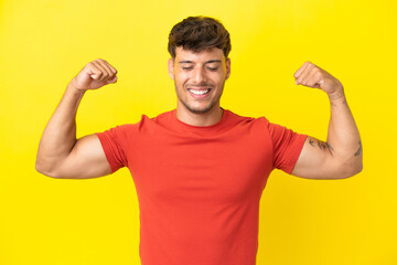 Young caucasian handsome man isolated on yellow background doing strong gesture