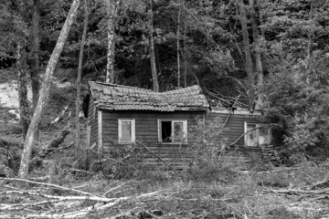 Deserted farm house with caved in roof shot in monochrome. Migration concept.