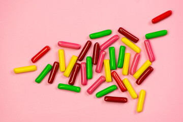 Multicolored rectangular candies on a pink background.