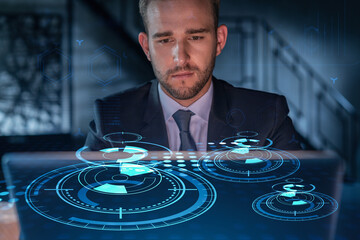 Handsome businessman in suit at workplace working with laptop to optimize development by implying...