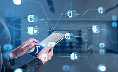 Businesswoman in formal suit is browsing the Internet in tablet device. Blue glowing information protection padlock icons. Concept of cyber security and data storage