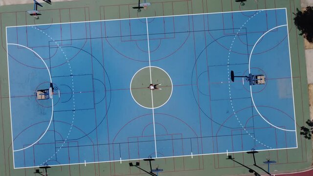 Toma aerea de drone en 4k de chico joven en pista de baloncesto en exterior