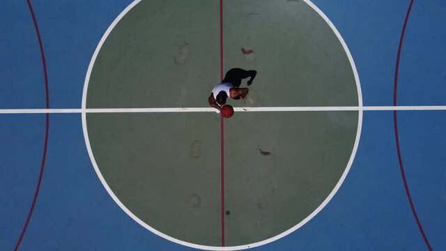 Toma aerea de drone en 4k de chico joven en pista de baloncesto en exterior