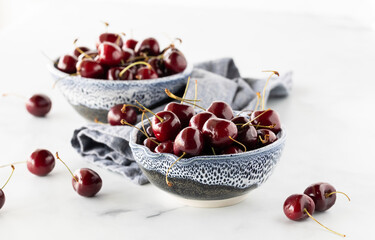 Two decorative pottery bowls filled with chelan cherries, ready for eating.
