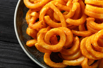 Golden Spicy Seasoned Curly Fries on rustic plate. ready to eat