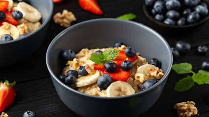 Healthy Oatmeal porridge breakfast with strawberry, blueberry, banana and honey