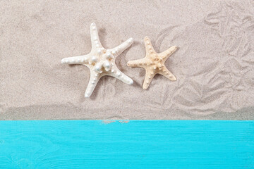 Fototapeta na wymiar Starfishes on the sand wooden board top view