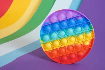 trend toy antistress pop it on a rainbow background, fidget toy, popping bubbles and calm down, development of the motor skills of hands and fingers - obrazy, fototapety, plakaty