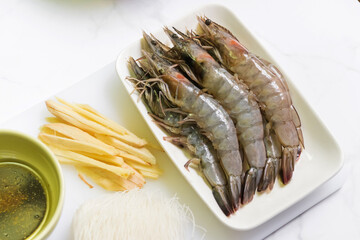 Ingredients for shrimp potted with glass noodle recipe. shrimp, glass noodle, three spice seasoning sauce and ginger sliced. Top view on white table background.