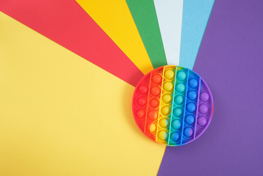 toy antistress pop it on a rainbow background, fidget toy, popping bubbles and calm down, development of the motor skills of hands and fingers