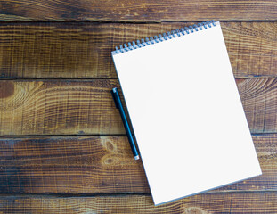 White album sheet on a wooden table. White sheet with a handle on the right side of the frame. Top view. Notebook for schedules. Copy space.