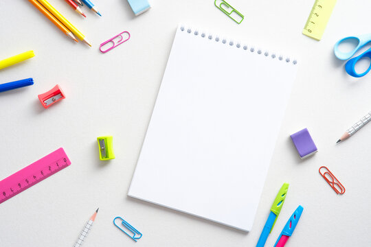 Flat lay colorful school supplies and paper notepad on white background. Back to school concept. Top view with copy space
