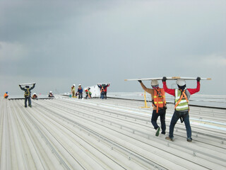 Workers Carry Solar PV Panel on Roof Installation