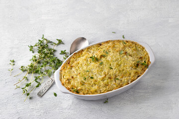 Cabbage casserole with lentils and cream, garnished with thyme in a ceramic baking dish on a light gray background, top view