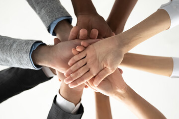 Crop close up of diverse international people join stack hands in pile motivated for shared team success or achievements. Multiethnic employees involved in teambuilding activity. Teamwork concept.