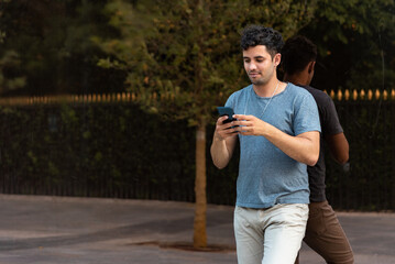 Young latin man in the park using the mobile phone.