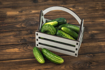 A box of fresh cucumbers on a brown wooden table.
