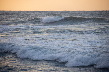 Orange color sunset over the sea, waves on the beach