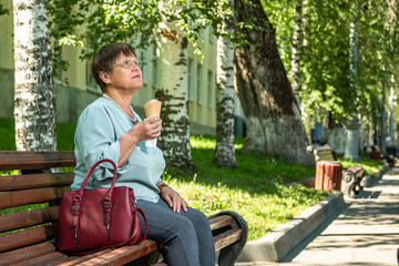 Fototapeta premium Grandma is eating ice cream in a summer park.