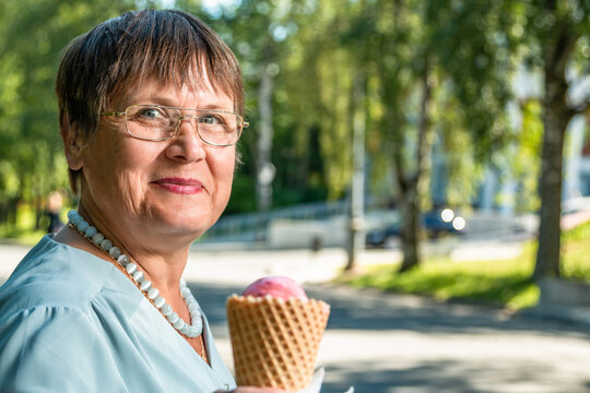 Grandma is eating ice cream in a summer park.