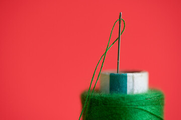 Hand sewing needle and thread close up in red background