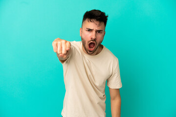 Young caucasian man isolated on blue background frustrated and pointing to the front