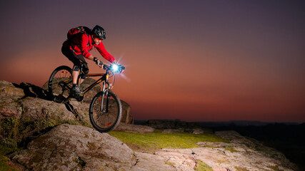 Fototapeta na wymiar Cyclist Riding the Mountain Bike on Rocky Trail at Night. Extreme Sport and Enduro Biking Concept.