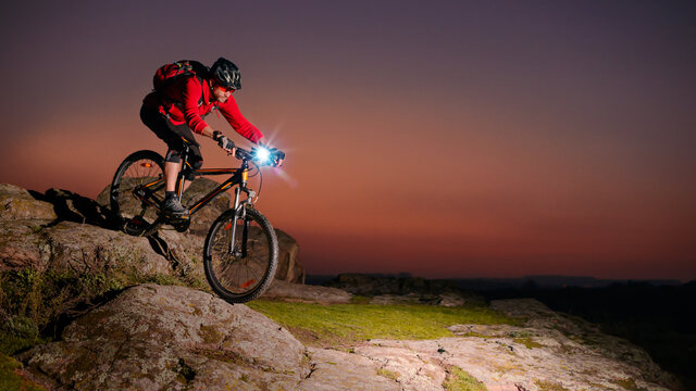 Cyclist Riding the Mountain Bike on Rocky Trail at Night. Extreme Sport and Enduro Biking Concept.