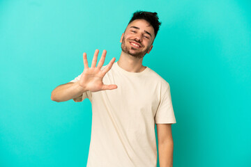 Fototapeta premium Young caucasian man isolated on blue background counting five with fingers