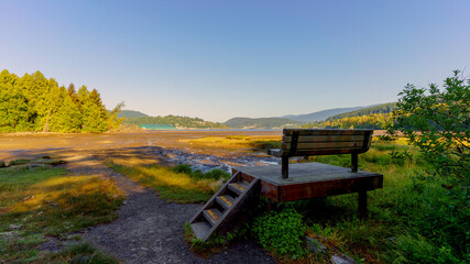 Fototapeta premium Raised viewing platform and bench overlooking mudflats during low tide for Burrard Inlet on Shoreline Trail at Port Moody - early summer morning during heatwave