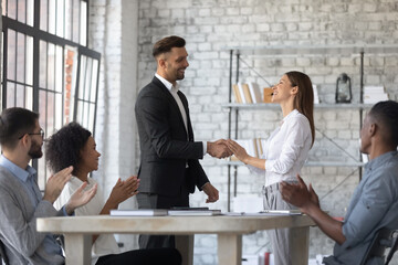 Happy young Caucasian businessman or boss shake hand of excited female colleague or partner close...