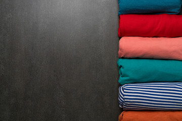 close up of rolled colorful t shirt clothes on wooden table background - obrazy, fototapety, plakaty